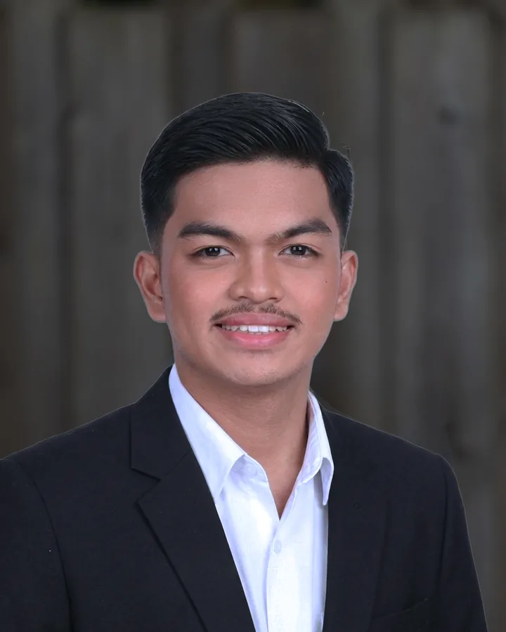 Evan Exanes in a dark suit and white shirt, smiling